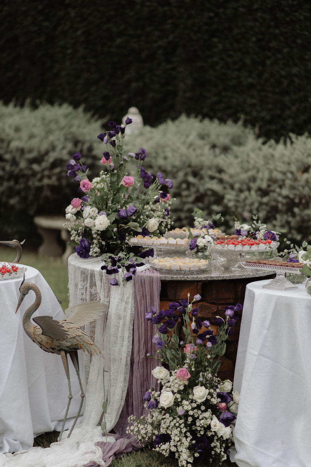 Mesa de doces decorada com flores em tons de roxo e rosa