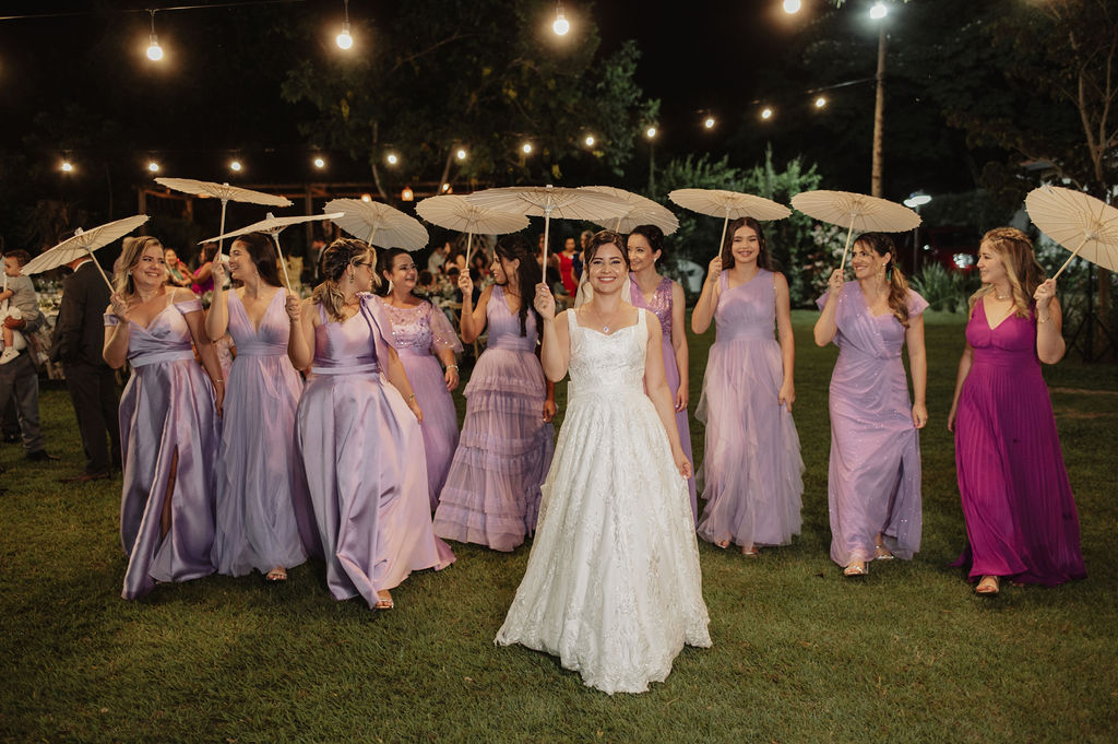 Noiva com madrinhas em vestidos lilás segurando sombrinhas